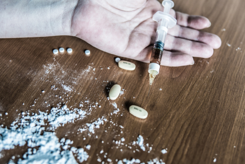 person holding a syringe with pills and powder on the table