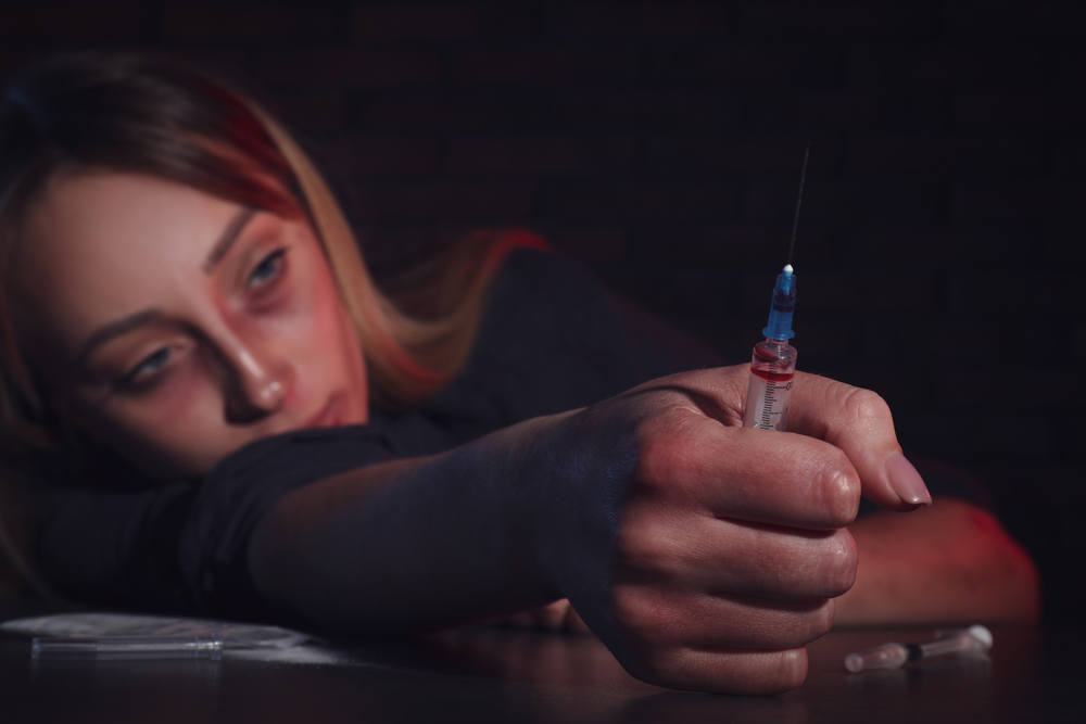 woman holding a syringe after shooting meth